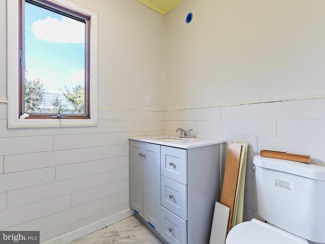 bathroom with marble finish floor, a wainscoted wall, vanity, and toilet