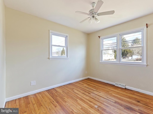 unfurnished room featuring light wood-style floors, a healthy amount of sunlight, visible vents, and baseboards