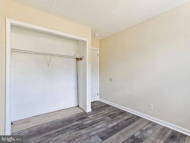 unfurnished bedroom with baseboards, a closet, and wood finished floors