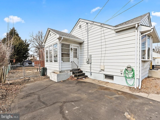 view of property exterior with entry steps, a patio, a shingled roof, and fence