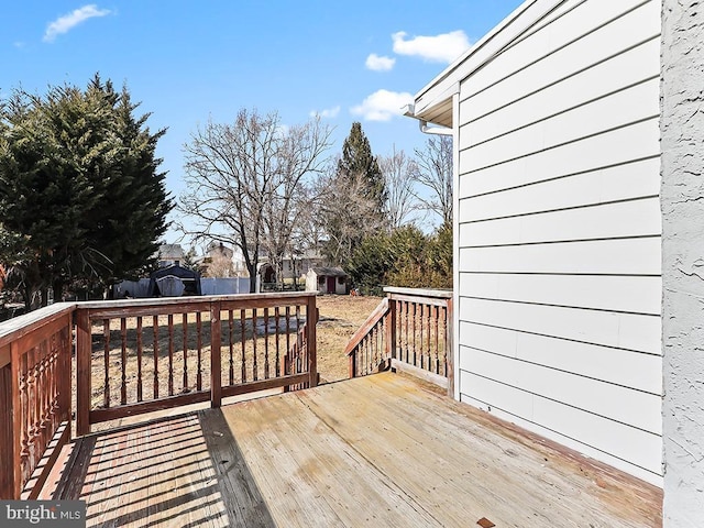 wooden terrace with a storage shed and an outbuilding