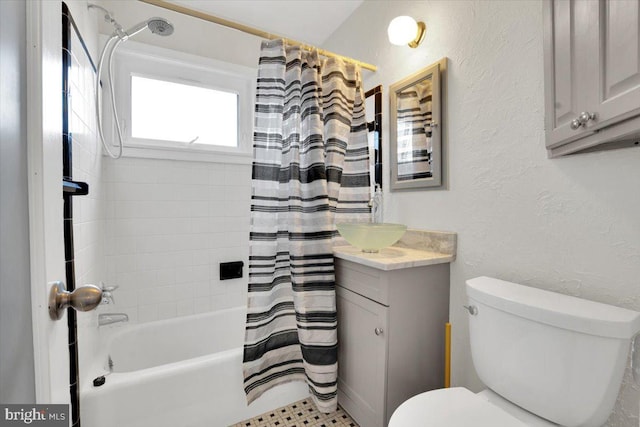 full bath with a textured wall, shower / bath combo, vanity, and toilet