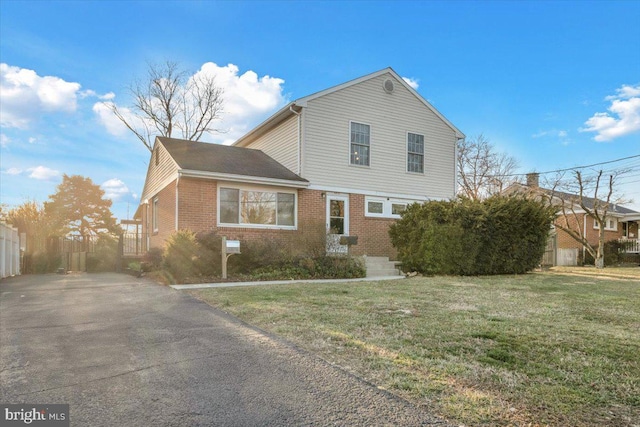 view of home's exterior with a yard, brick siding, and fence