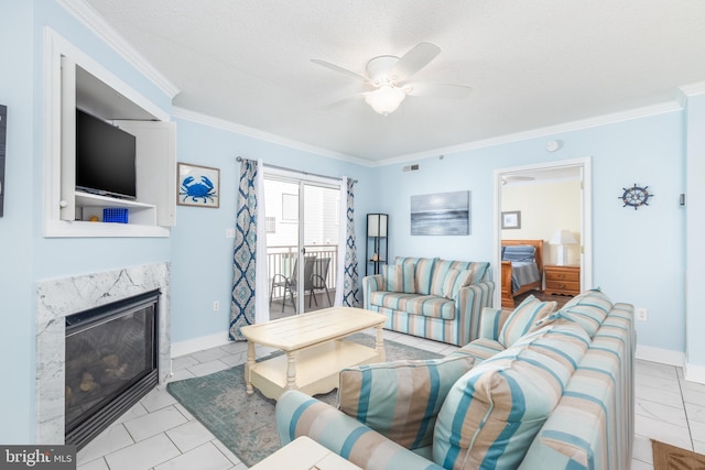 living area featuring baseboards, ceiling fan, a textured ceiling, crown molding, and a high end fireplace