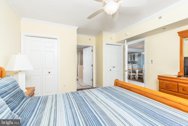 unfurnished bedroom with ornamental molding, ceiling fan, a textured ceiling, and two closets