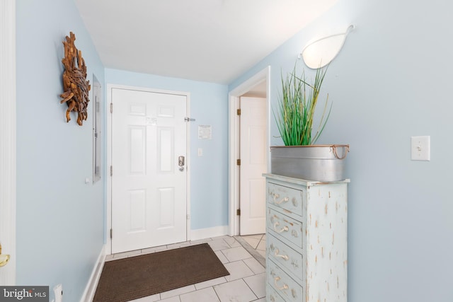 foyer entrance featuring light tile patterned floors and baseboards