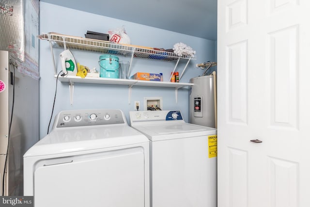 washroom featuring laundry area, water heater, and washing machine and clothes dryer