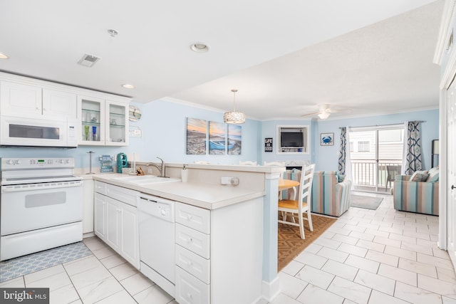 kitchen featuring a peninsula, white appliances, a sink, visible vents, and ornamental molding