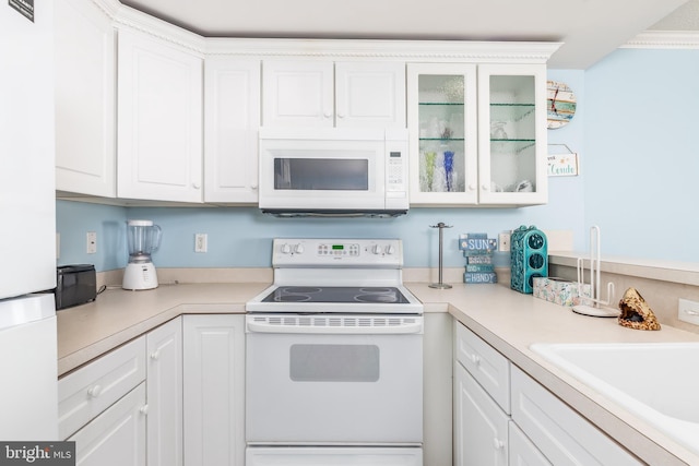 kitchen featuring light countertops, white appliances, a sink, and white cabinets