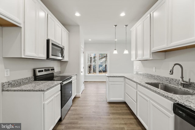 kitchen with recessed lighting, stainless steel appliances, wood finished floors, a sink, and white cabinetry