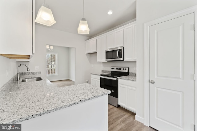 kitchen with white cabinets, light wood-style flooring, light stone counters, stainless steel appliances, and a sink