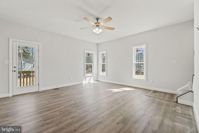 unfurnished living room with a healthy amount of sunlight, ceiling fan, baseboards, and wood finished floors