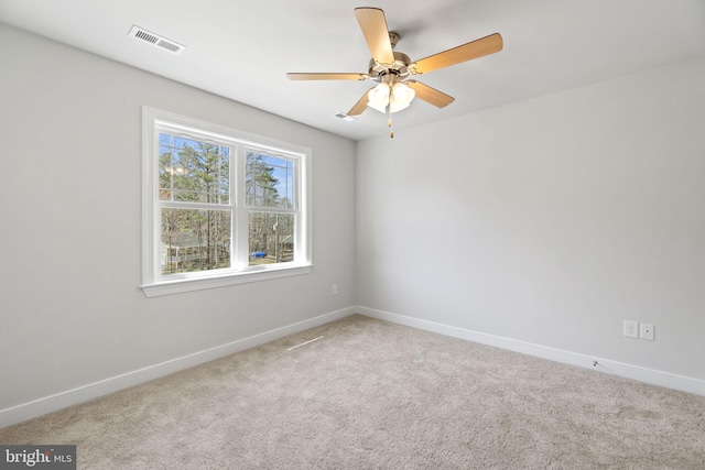 carpeted spare room with baseboards, visible vents, and ceiling fan