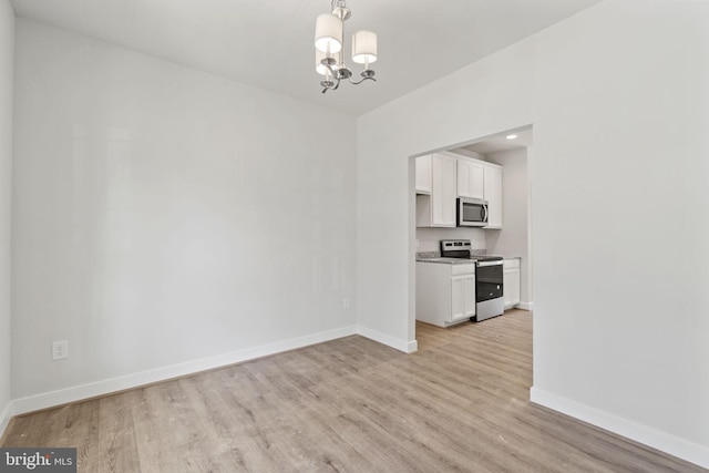 unfurnished dining area with a chandelier, light wood-style floors, and baseboards