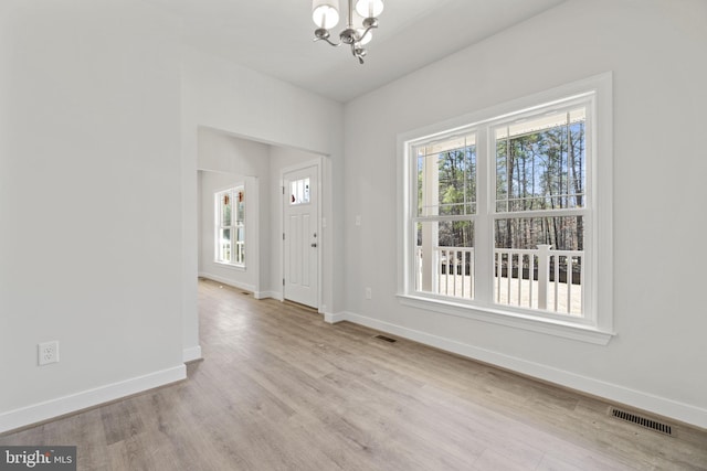 foyer entrance featuring baseboards, visible vents, and wood finished floors