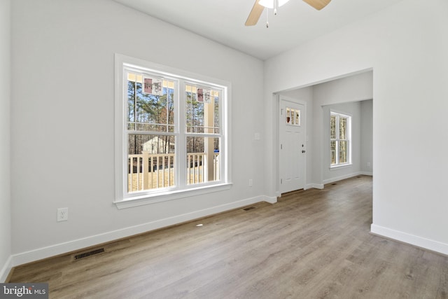 unfurnished room with baseboards, plenty of natural light, visible vents, and wood finished floors