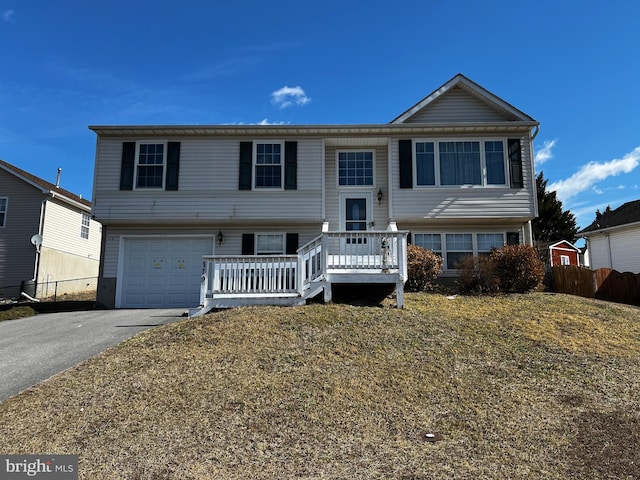 bi-level home with driveway, a garage, and fence