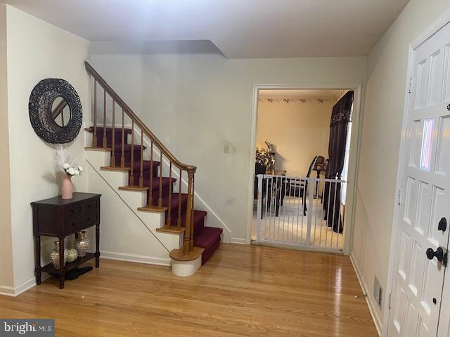 entryway with stairs, wood finished floors, and baseboards