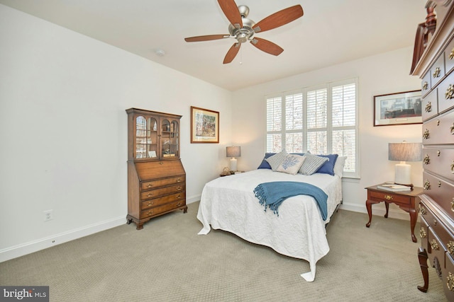 bedroom featuring light carpet, a ceiling fan, and baseboards