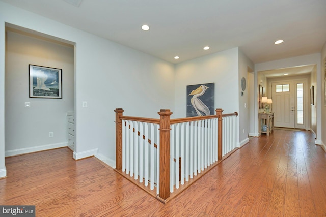 hallway with recessed lighting, baseboards, an upstairs landing, and wood finished floors