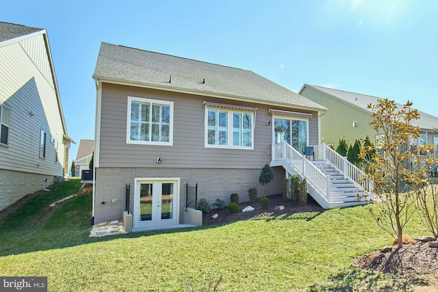 back of house featuring a shingled roof, french doors, stairway, a yard, and brick siding