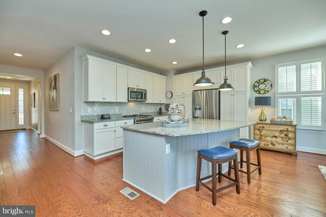 kitchen with stainless steel appliances, light wood finished floors, visible vents, and white cabinetry