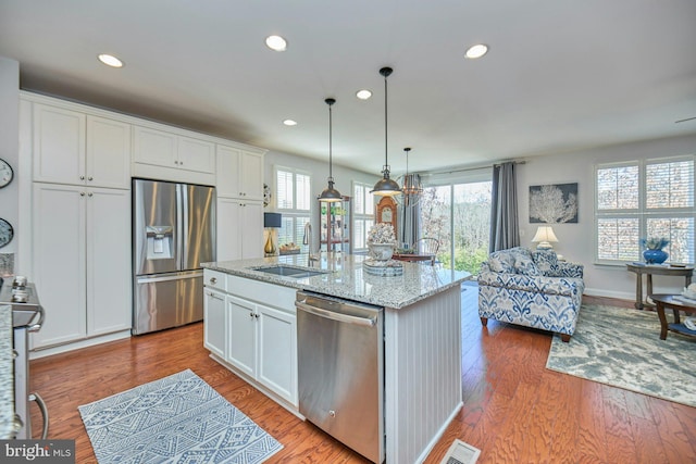 kitchen with stainless steel appliances, wood finished floors, a sink, and white cabinets