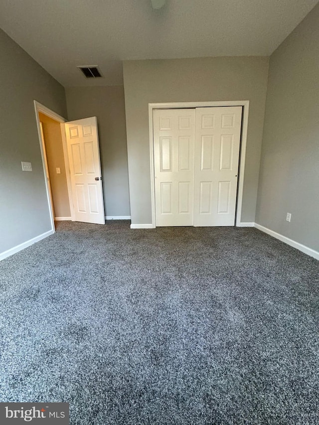 unfurnished bedroom featuring carpet, a closet, visible vents, and baseboards