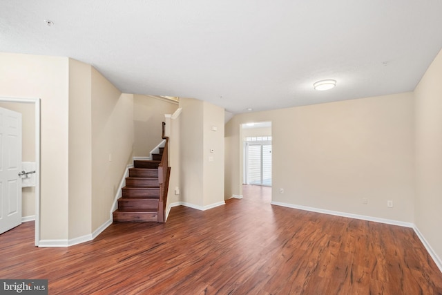 unfurnished living room with stairs, baseboards, and wood finished floors