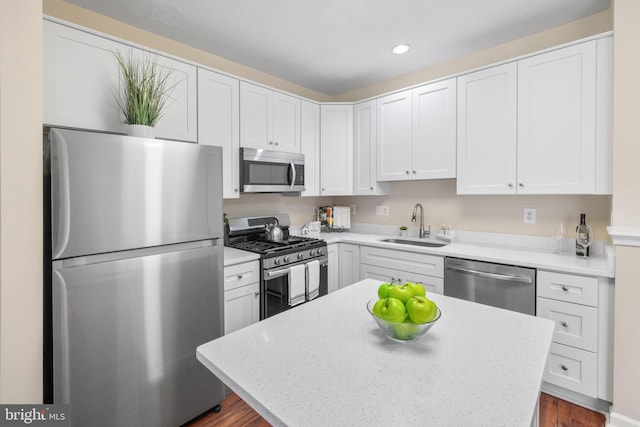 kitchen with white cabinets, a kitchen island, appliances with stainless steel finishes, a sink, and recessed lighting