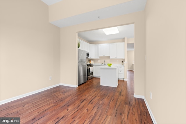 kitchen featuring baseboards, white cabinets, light countertops, appliances with stainless steel finishes, and dark wood finished floors