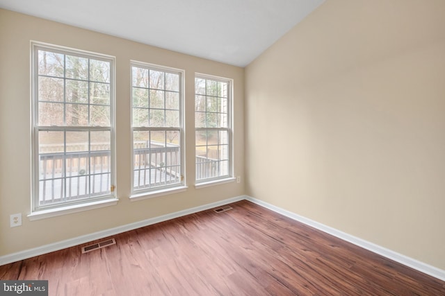 spare room featuring lofted ceiling, dark wood-style flooring, visible vents, and baseboards