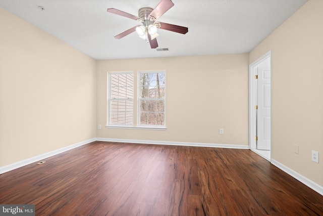 unfurnished room with ceiling fan, dark wood finished floors, visible vents, and baseboards