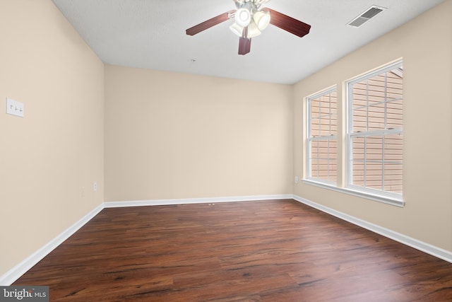 spare room featuring dark wood-style flooring, visible vents, ceiling fan, and baseboards