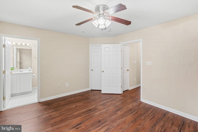 unfurnished bedroom with ensuite bathroom, wood finished floors, a ceiling fan, and baseboards