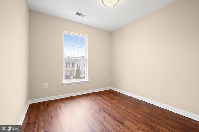 empty room with visible vents, dark wood finished floors, and baseboards