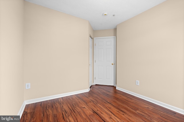 empty room with dark wood finished floors and baseboards