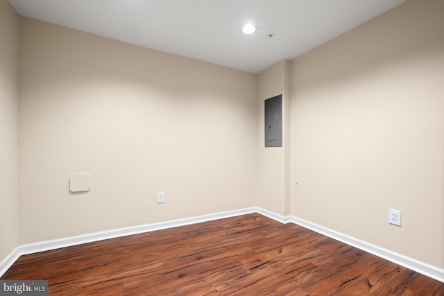 empty room with dark wood-style flooring, electric panel, and baseboards