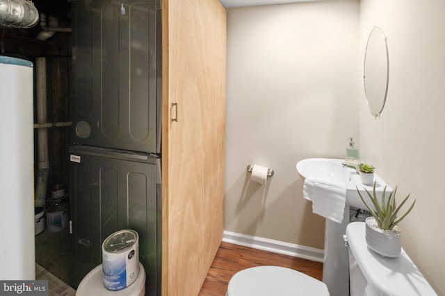 half bathroom with water heater, wood finished floors, toilet, and baseboards