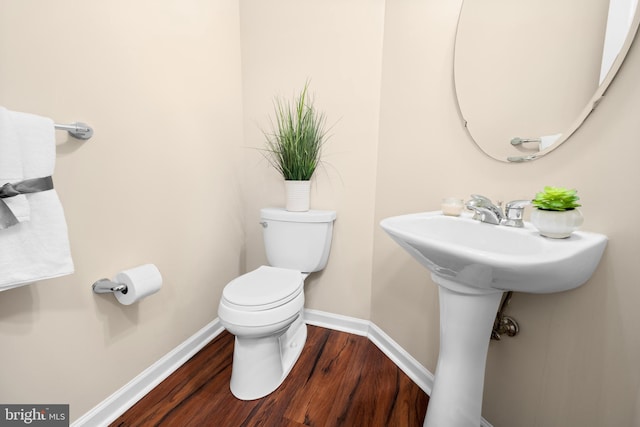 half bathroom featuring baseboards, toilet, and wood finished floors