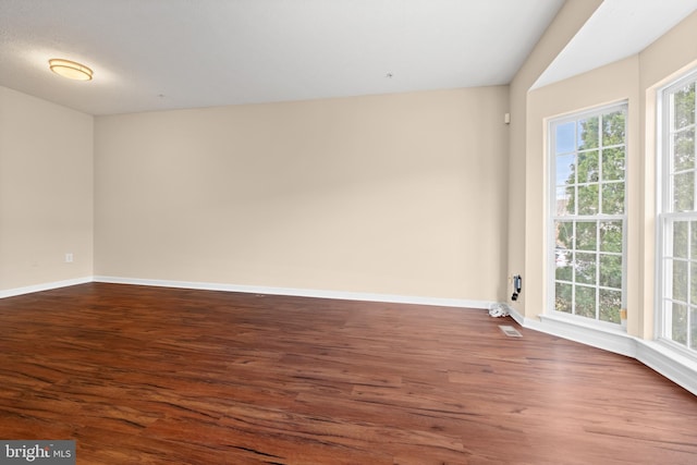 spare room with dark wood-style floors and baseboards