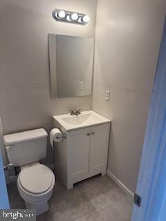 bathroom featuring toilet, baseboards, and vanity