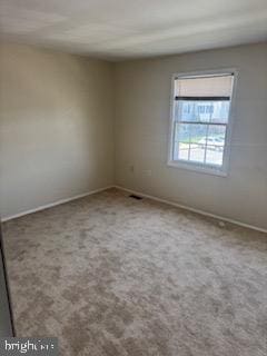 carpeted spare room featuring baseboards