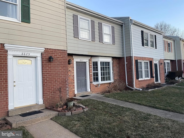 view of property featuring a front lawn and brick siding