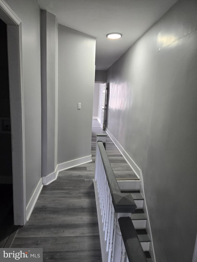 hallway featuring baseboards and dark wood-type flooring