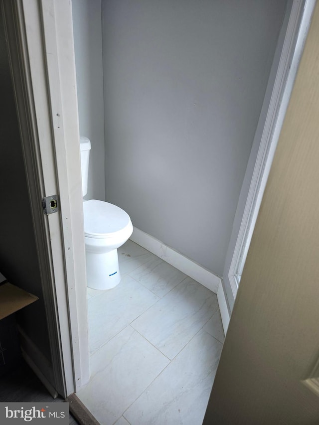 bathroom featuring marble finish floor, toilet, and baseboards