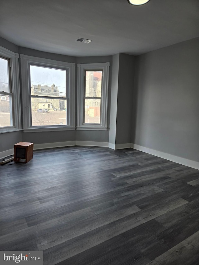 unfurnished room with dark wood-style flooring and baseboards