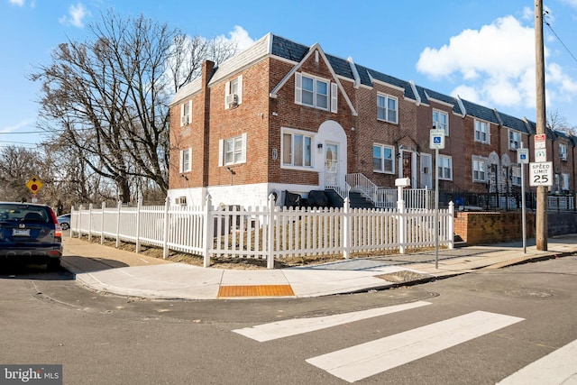 multi unit property with a fenced front yard and brick siding