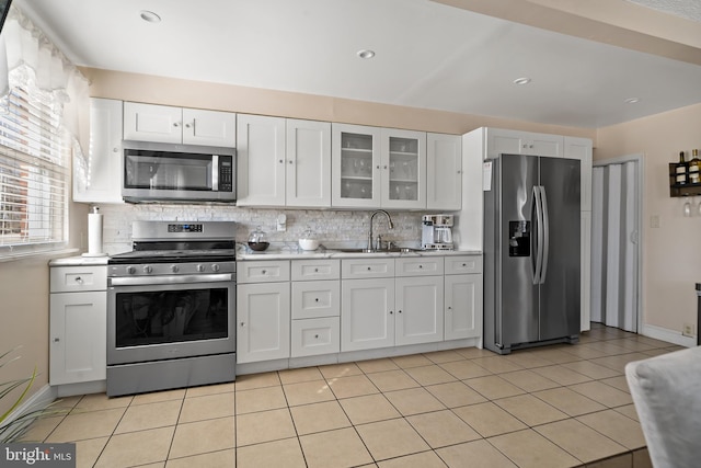 kitchen with a sink, white cabinetry, light countertops, appliances with stainless steel finishes, and tasteful backsplash