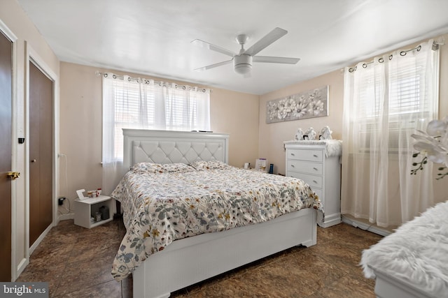 bedroom featuring ceiling fan, multiple windows, and baseboards